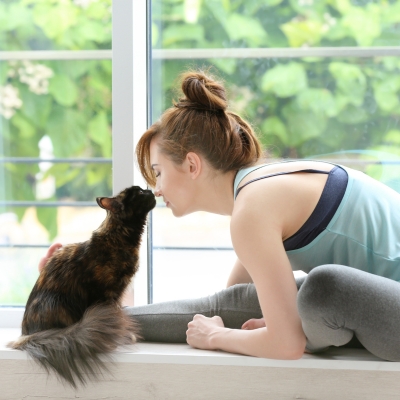 Flow A woman in yoga gear with cat loving