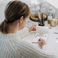 A woman writing her goals in a note pad