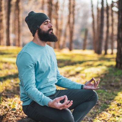 Vision Menu Icons Tobassa (3) A man dressed in beanie and sweat top meditating in forest in sunlight